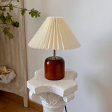 Compact wood table lamp with cream pleated shade and leafy branch