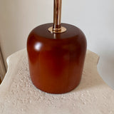 Rounded cylindrical walnut-tone wood lamp base and slim metal stem