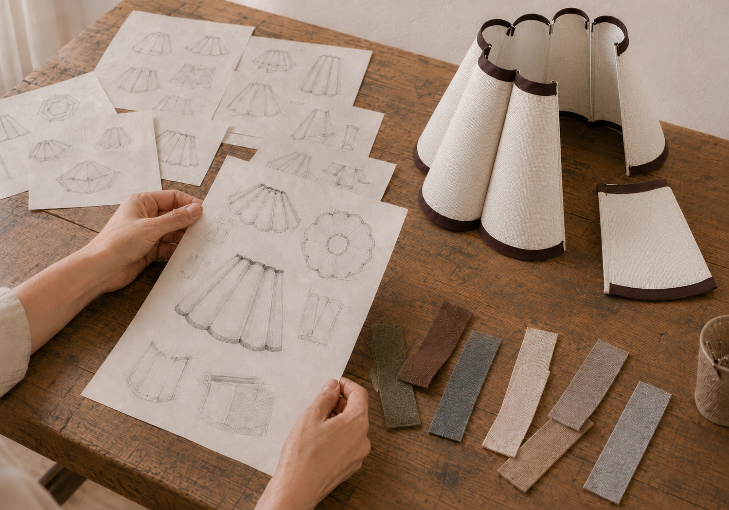 Lampshade frames, fabric panels, swatches, and tools arranged during product development.