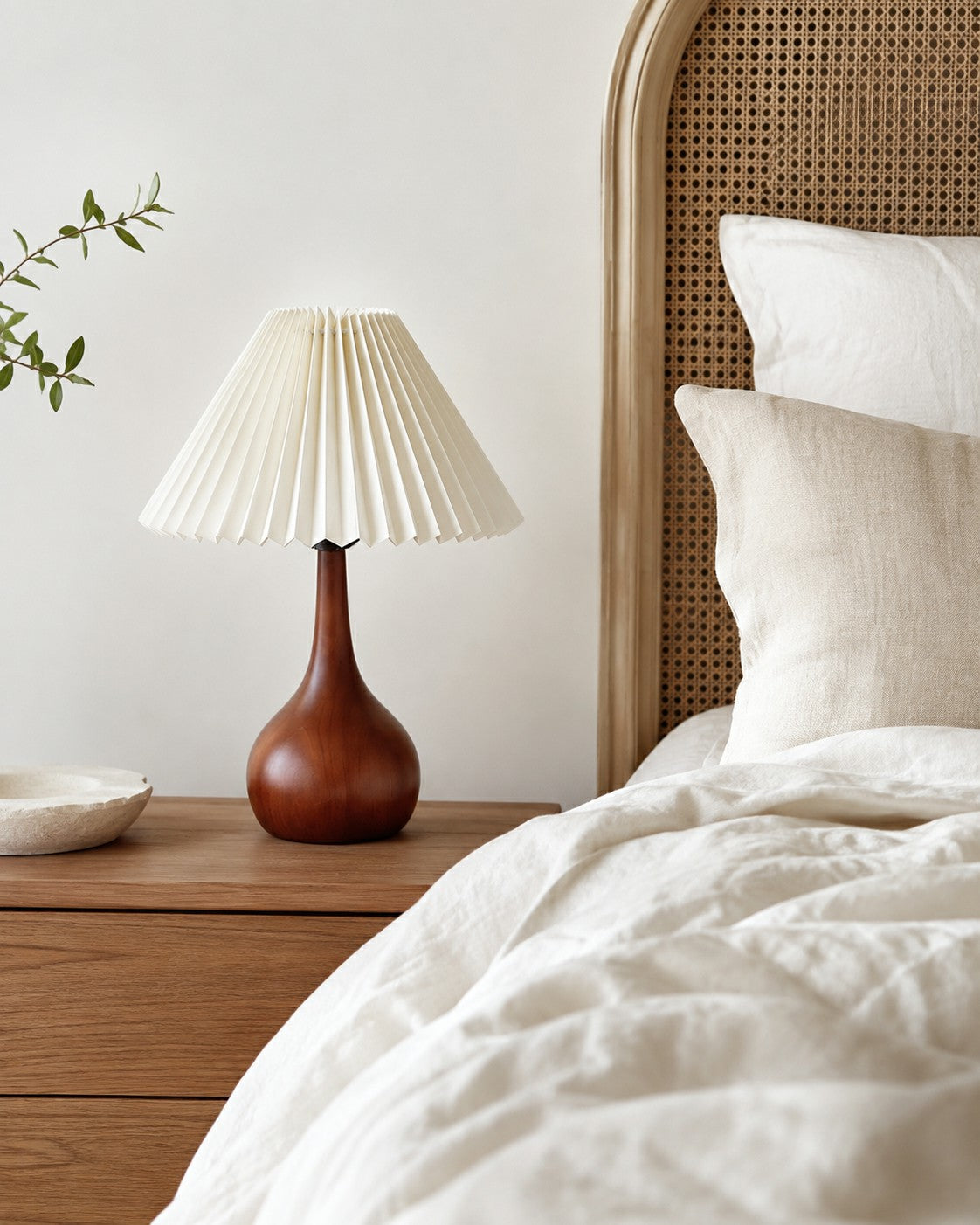 Walnut-tone table lamp styled beside soft neutral fabric